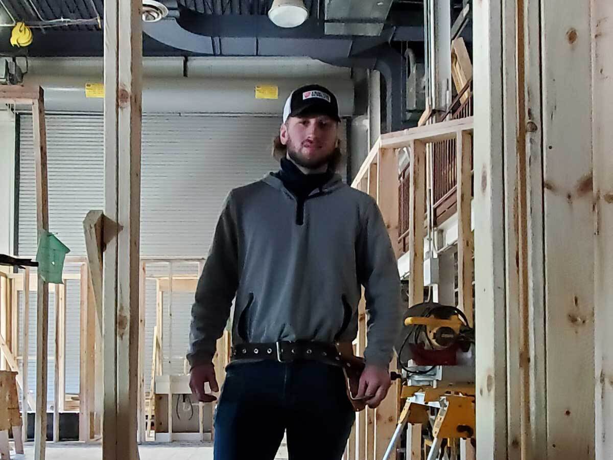 standing in a house his class is currently building in the construction trades lab